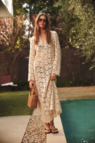 Woman in a floral dress standing by a pool with greenery in the background