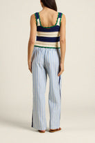 Woman wearing a striped sleeveless top and wide-leg pants on a plain background