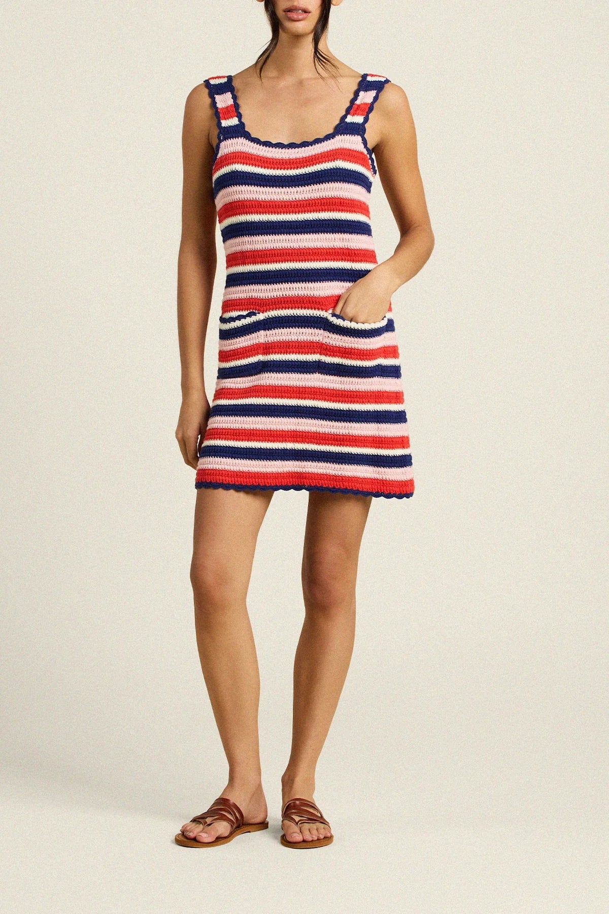 Woman wearing a red, white, and blue striped dress on a beige background