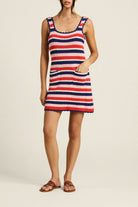 Woman wearing a red, white, and blue striped dress on a beige background