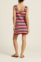 Person wearing a red, white, and blue striped dress on a beige background