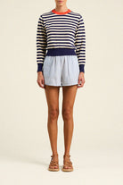 Person wearing a striped sweater and shorts on a plain background