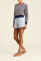 Person wearing a striped sweater and shorts on a plain background