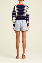 Person wearing a striped sweater and shorts on a plain background