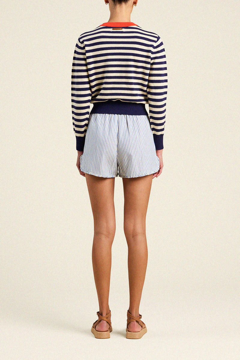 Person wearing a striped sweater and shorts on a plain background