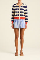 Person wearing a striped sweater and shorts on a plain background