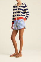 Person wearing a striped sweater and shorts on a plain background