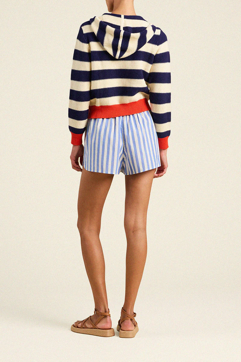 Person wearing a striped sweater and shorts on a plain background
