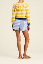 Person wearing a striped yellow sweater and shorts on a plain background