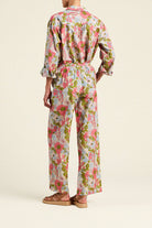 Person wearing a floral jumpsuit on a beige background