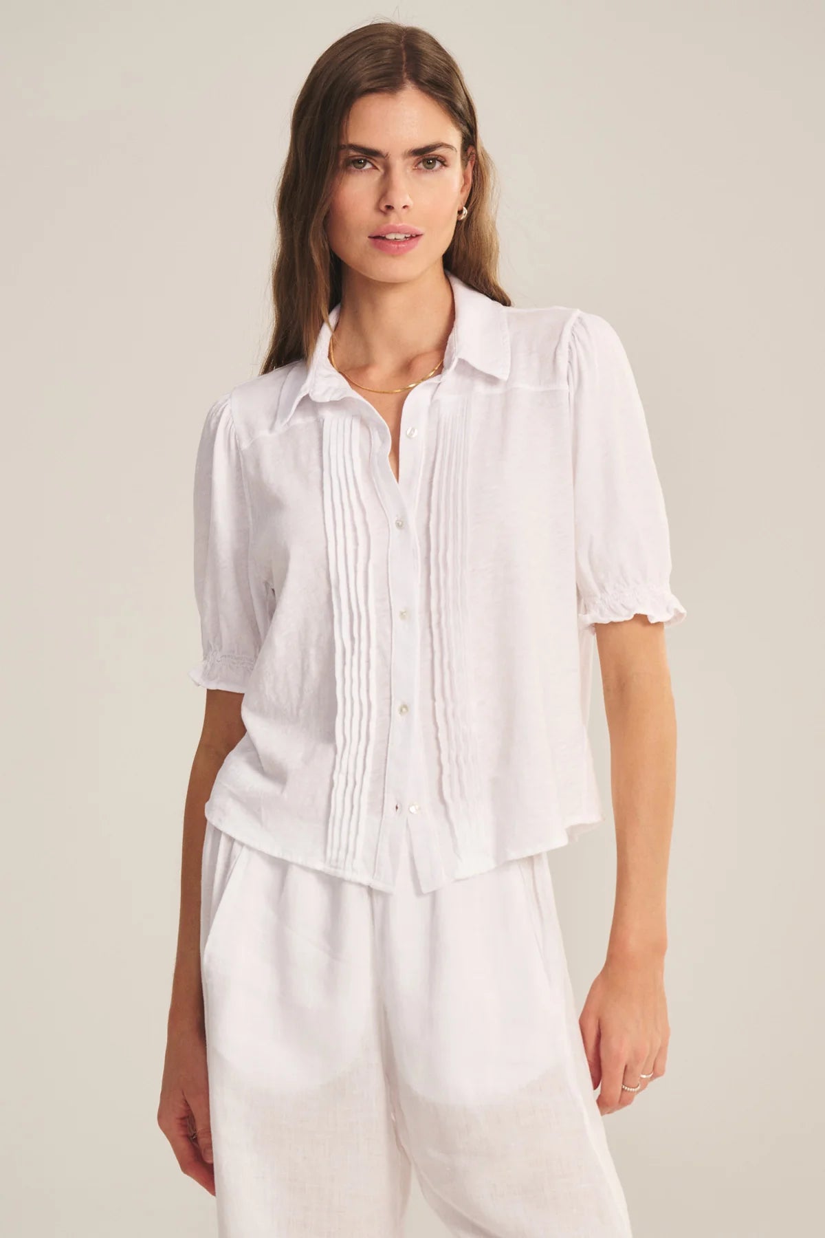 Woman wearing a white blouse with short sleeves on a plain background