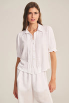 Woman wearing a white blouse with short sleeves on a plain background