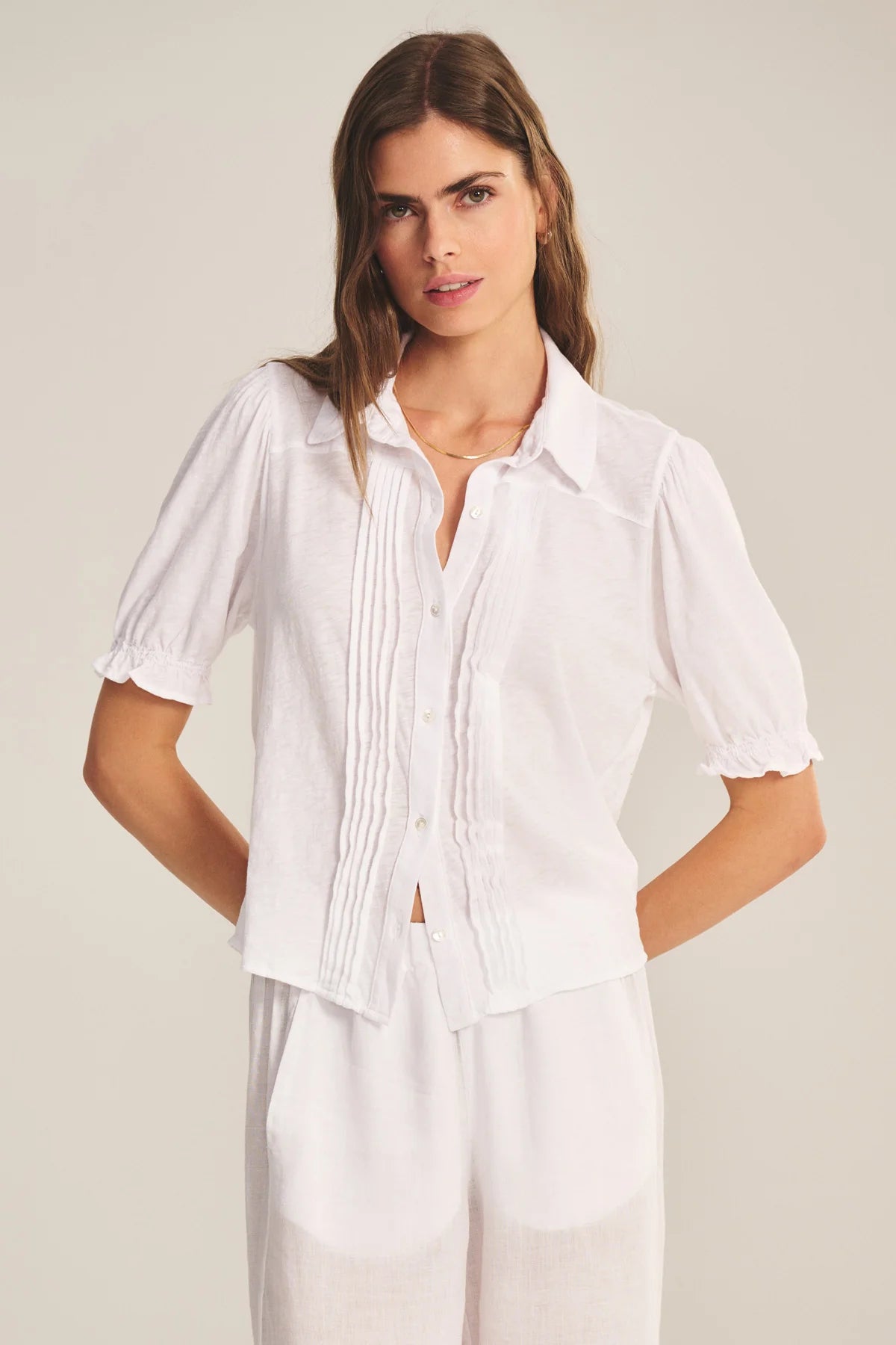 Woman wearing a white blouse with short sleeves on a plain background
