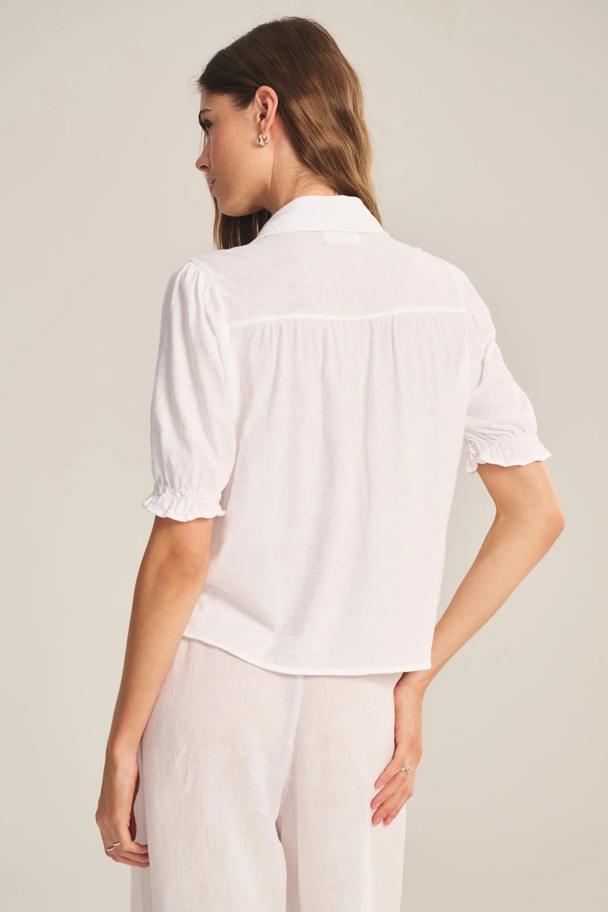 Woman wearing a white blouse with short sleeves on a plain background
