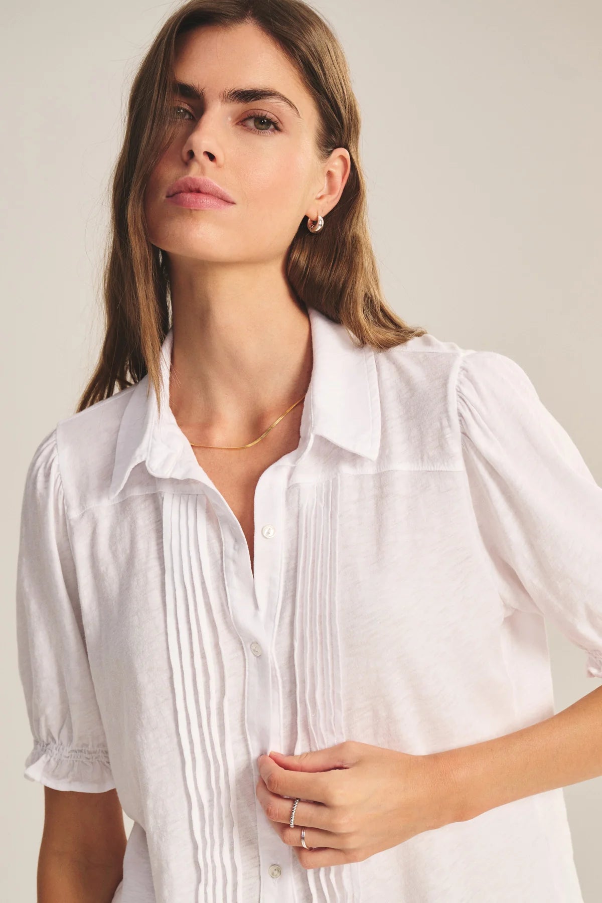 Woman wearing a white blouse against a plain background