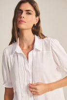 Woman wearing a white blouse against a plain background