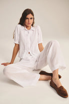 Woman wearing a white outfit with brown shoes on a plain background