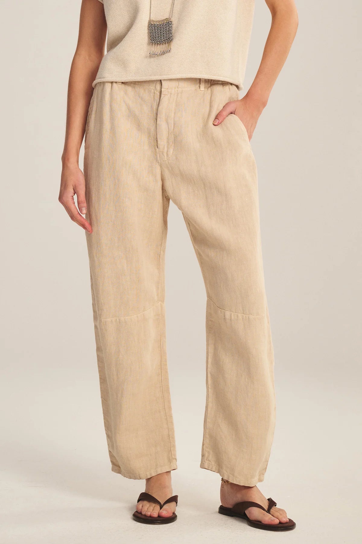 Person wearing beige linen pants on a plain background
