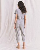 Woman wearing a gray outfit standing against a white curtain