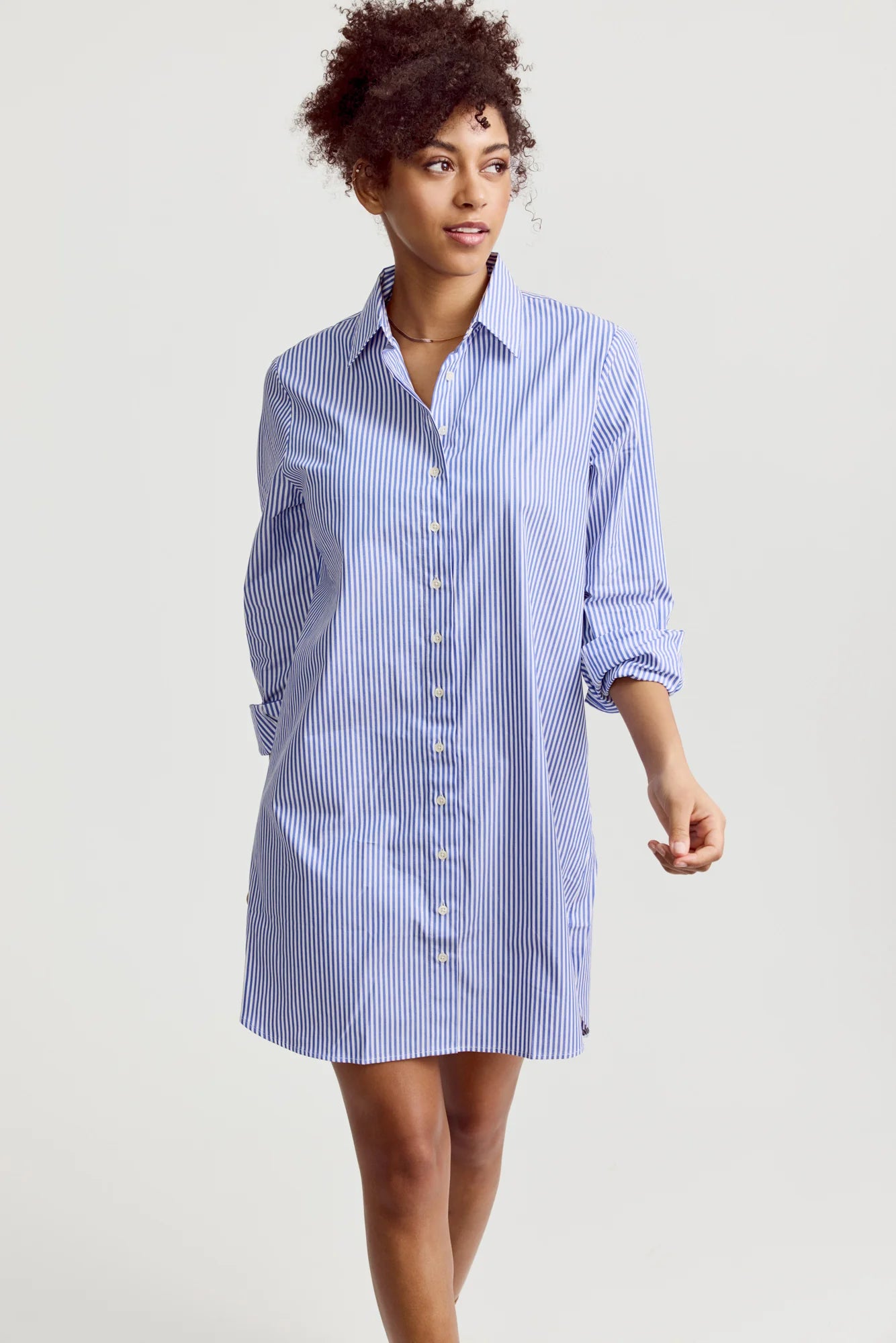 Woman wearing a blue and white striped shirt dress on a plain background
