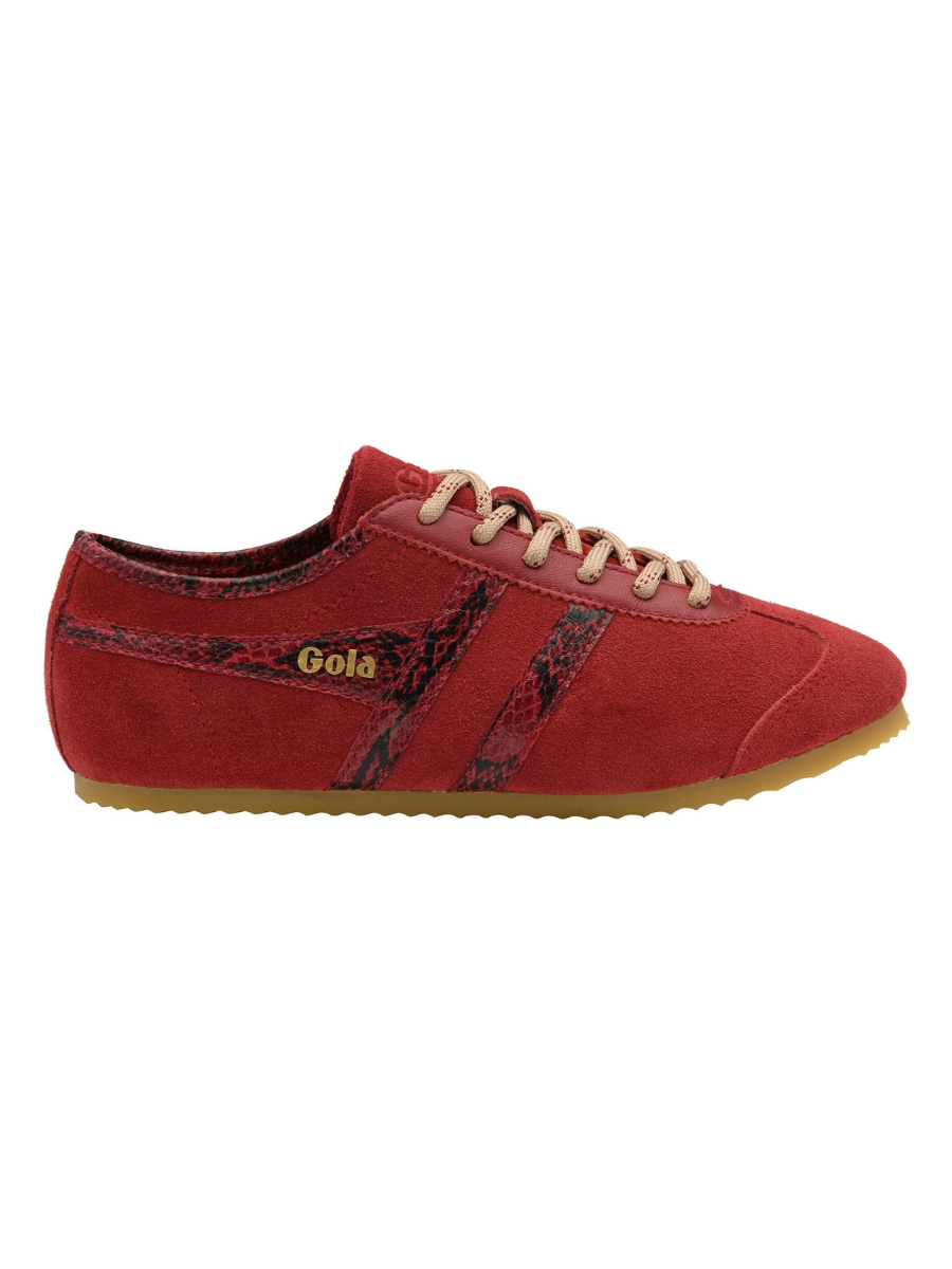 A red suede sneaker with a dark patterned side stripe, beige laces, and a gum sole, shown from the side on a white background. The brand name 'Gola' is visible in gold on the side.