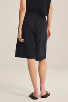 Person wearing black shorts on a beige background