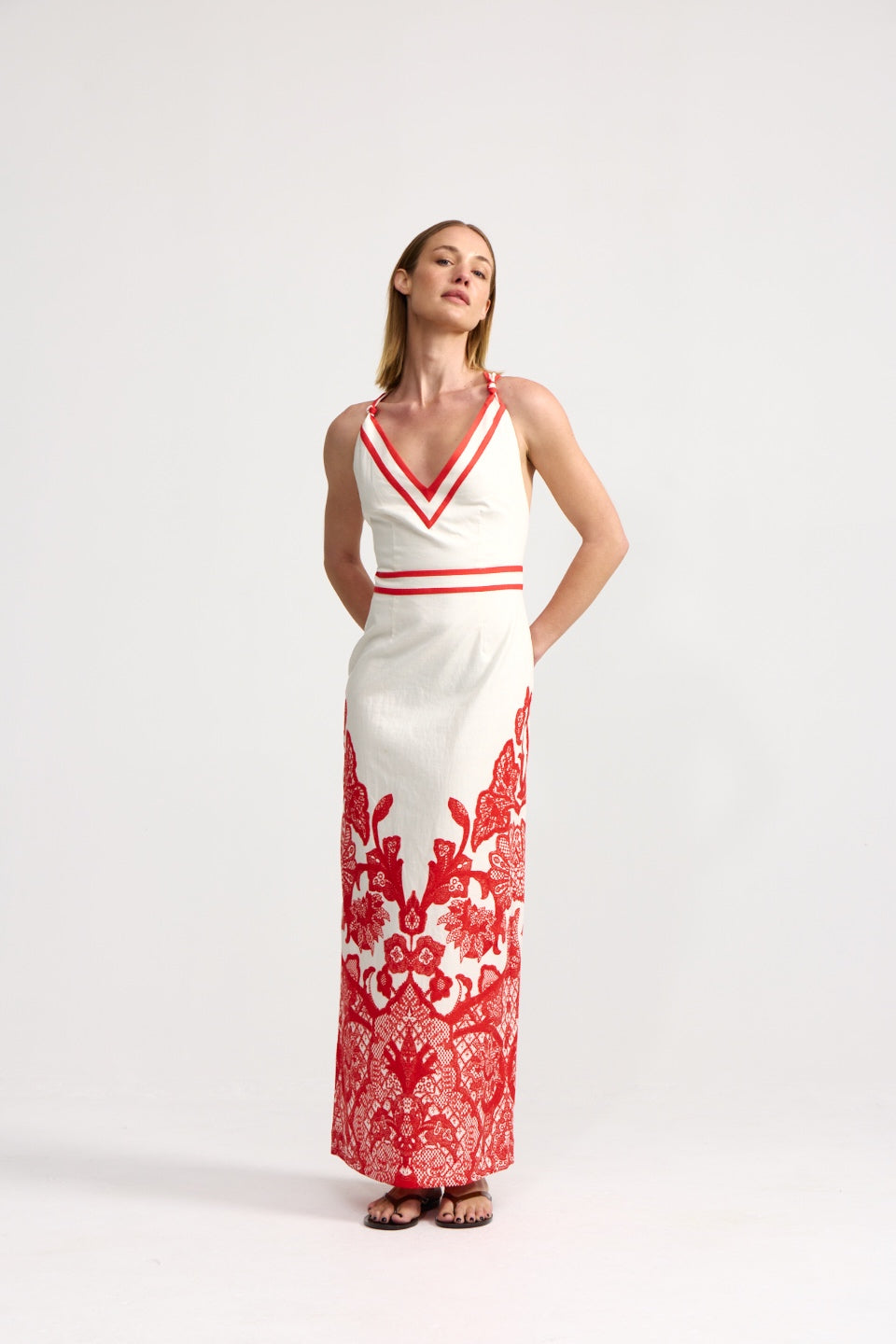Woman wearing a white dress with red floral patterns on a white background