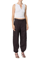 A model wearing dark brown baggy cargo pants with a white sleeveless crop top and strappy heels, shown against a plain white background.