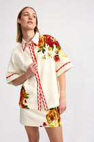 Woman wearing a floral blouse and skirt set on a white background