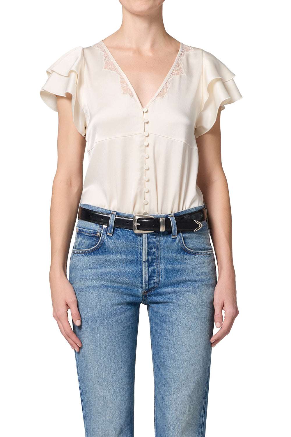 Person wearing a white blouse with ruffled sleeves and blue jeans on a white background
