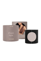 New York Nood Shape Tape hair product set featuring a taupe-gray jar labeled 'shape tape NEW YORK', a black outer sleeve with a circular cutout, and a backing card showing a model.