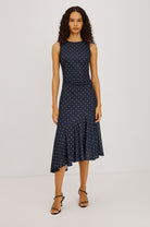 Woman wearing a navy dress with white polka dots on a white background