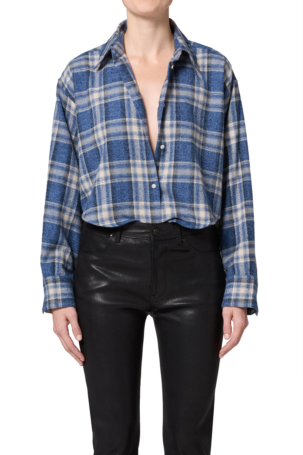 A model wearing a blue, white, and gray plaid button-down shirt tucked into black leather-look pants, shown from the neck down on a white background.