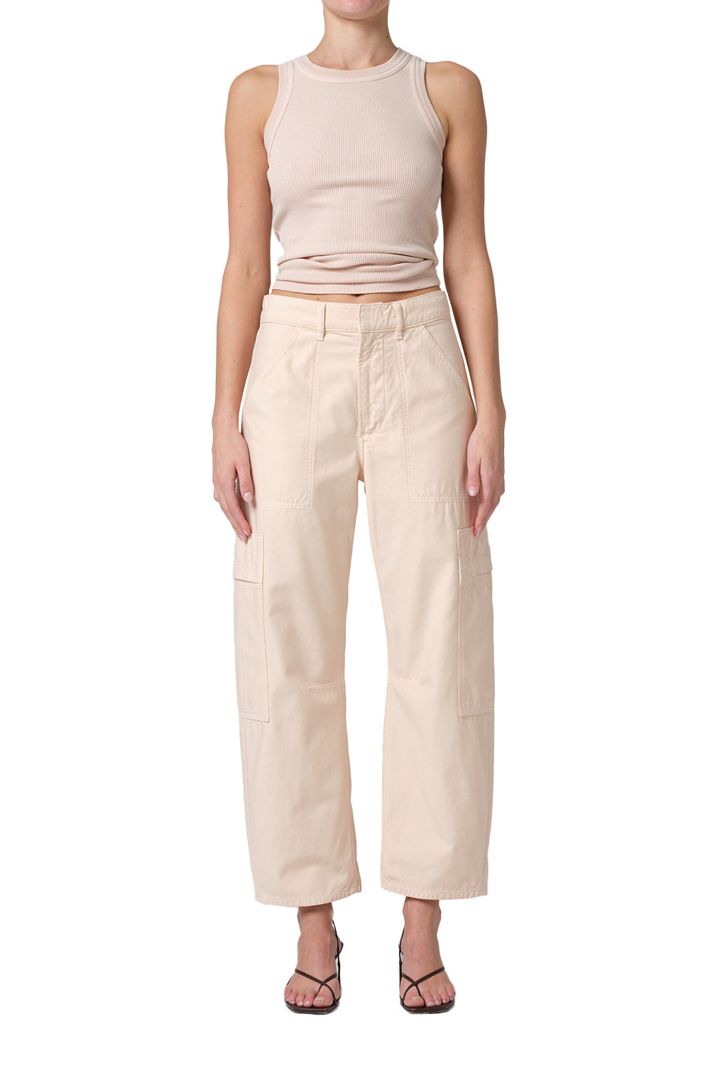 Woman wearing a beige tank top and pants on a white background