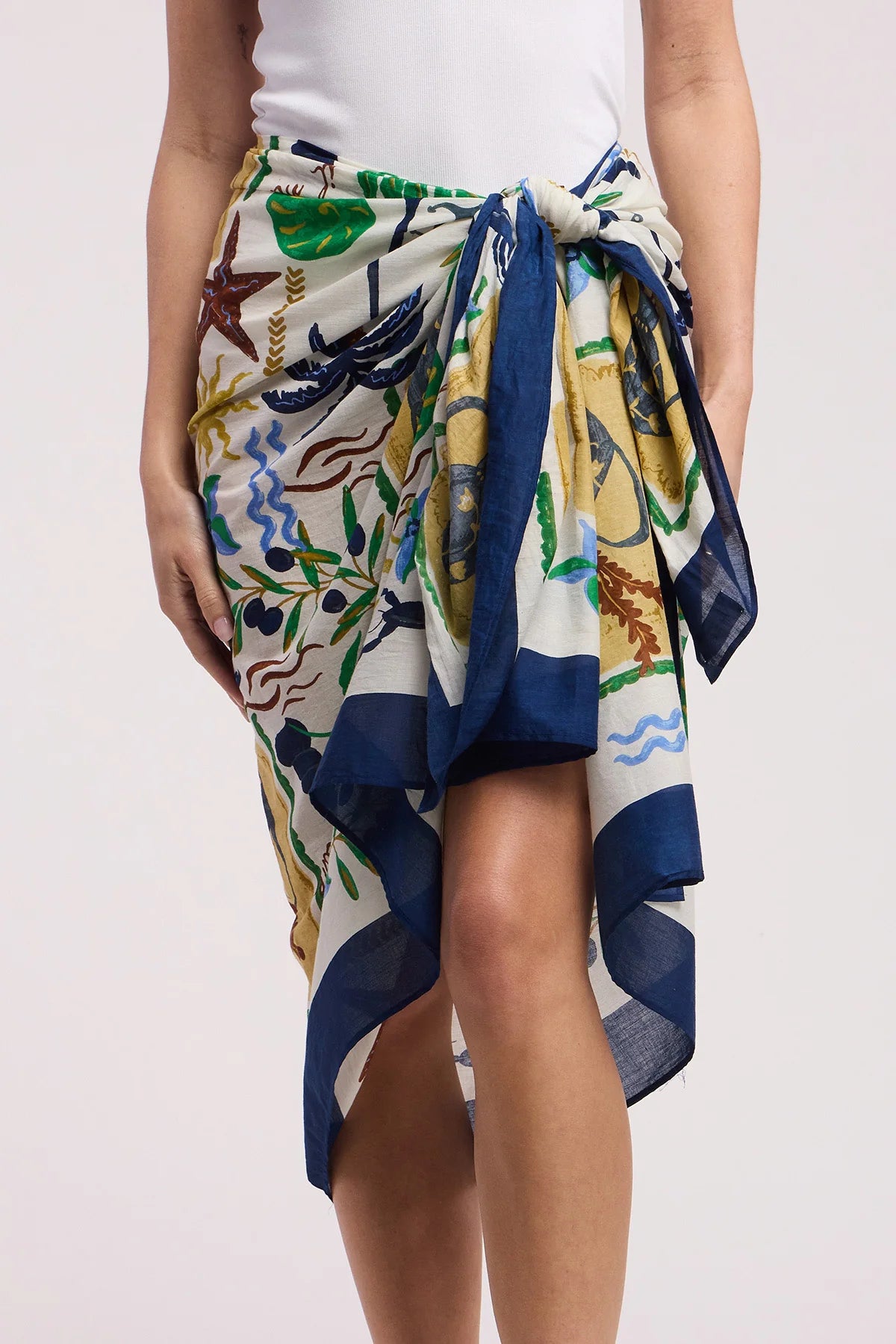 Person wearing a colorful floral and abstract patterned scarf on a plain background