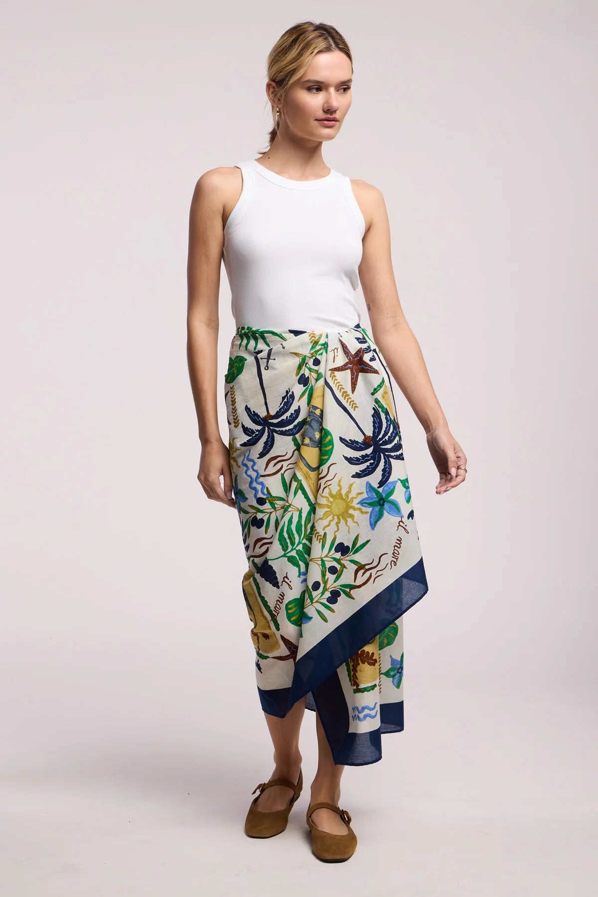Woman wearing a white top and a colorful floral skirt on a plain background