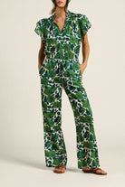 Woman wearing a green and white patterned jumpsuit on a plain background
