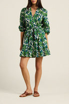Woman wearing a green and white patterned dress on a plain background