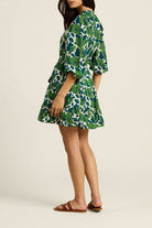 Woman wearing a green floral dress on a beige background